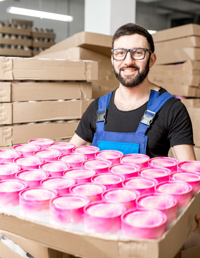 Portrait of a handsome worker in unifrom standing with paper tubes at the old printing manufacturing